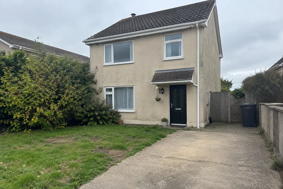 Sample house before: a detached two-storey house with beige render, white windows and a small porch roof over a black door.